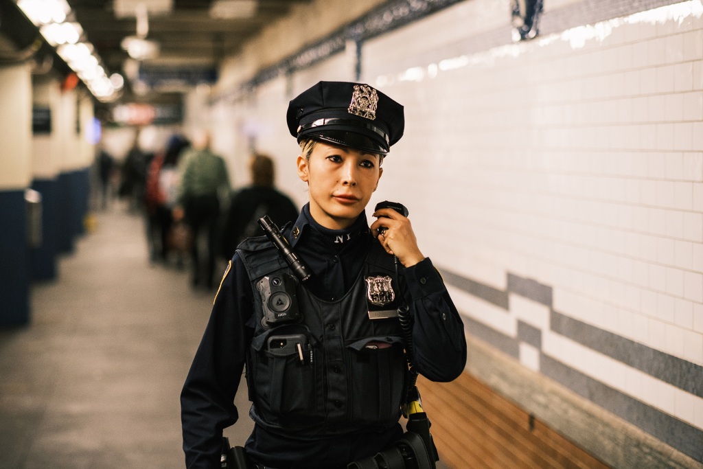 A female police officer speaking on her radio in an NYC subway station. 
